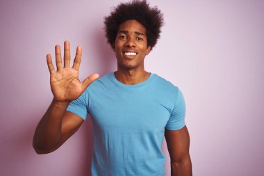 Afro saç ile Afrikalı Amerikan adam izole pembe arka plan üzerinde ayakta mavi t-shirt dikiliyor ve parmak sayısı beş ile işaret kadar güven ve mutlu gülümseyen.