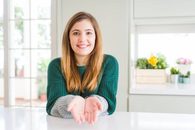 Rahat çizgili kazak giyen genç güzel artı boyutu kadın birlikte alma veya jest vererek el avuç içi ile gülümsüyor. Tutma ve koruma