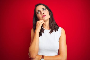 Beyaz elbise giyen genç güzel kadın, el ile kırmızı izole arka planda ayakta soru hakkında düşünme, dalgın ifade. Düşünceli bir yüz ile gülümsüyor. Şüphe kavramı.