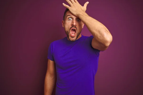 Young man wearing casual purple t-shirt over lilac isolated background surprised with hand on head for mistake, remember error. Forgot, bad memory concept.