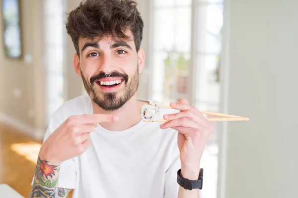 Νέος Άνθρωπος Που Τρώει Ασιατικό Σούσι Χρησιμοποιώντας Ξυλάκια Πολύ Χαρούμενο — Φωτογραφία Αρχείου