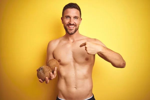 Young Handsome Shirtless Man Holding Exotic Tropical Coconut Isolated Yellow — Stock Photo, Image