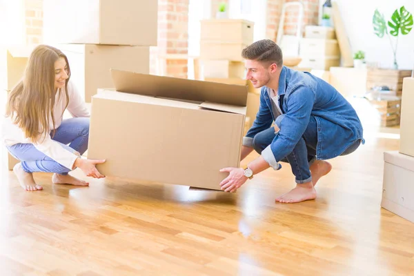 Schönes junges Paar, das verliebt lächelt und einen großen Karton in der Hand hält — Stockfoto