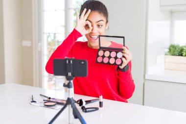 Genç African American etki unsuru kadın kayıt mutlu yüz gülümseyen ile öğretici parmak görünümlü göz el ile ok işareti yapıyor makyaj