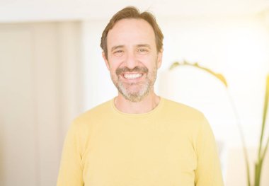 Evde kameraya bakarak gülümseyen yakışıklı orta yaş erkek