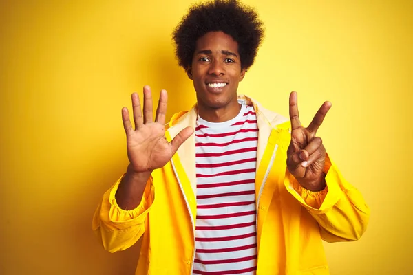 孤立した黄色の背景の上に立つアフロヘアのアフリカ系アメリカ人男性は 自信を持って幸せに微笑みながら 指番号7を示し 指を上げる — ストック写真