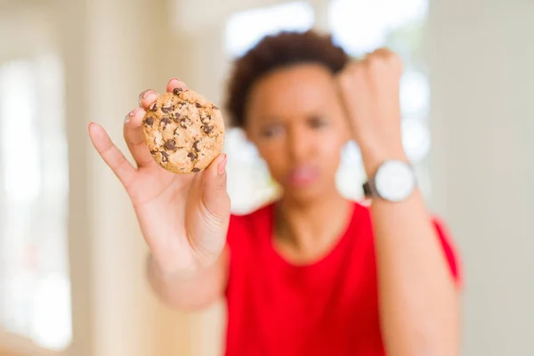 年轻的非洲裔美国妇女吃巧克力片饼干恼火和沮丧的喊声与愤怒 疯狂和大喊大叫与提高的手 愤怒的概念 — 图库照片