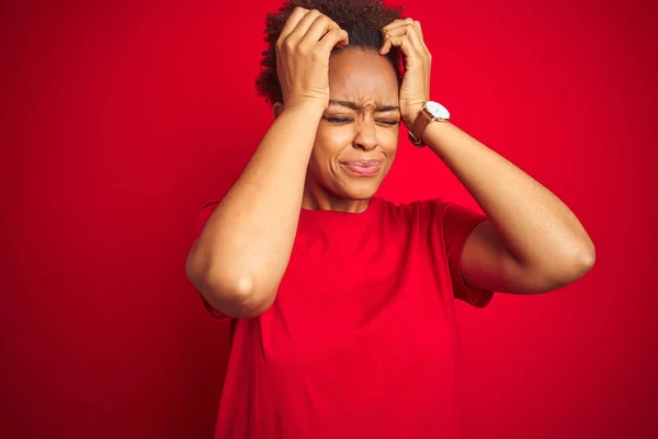 孤立した赤い背景の上にアフロ髪を持つ若い美しいアフリカ系アメリカ人女性は 頭痛に苦しんで絶望的で 痛みと偏頭痛のためにストレスを受けました 頭の上に手を置く — ストック写真