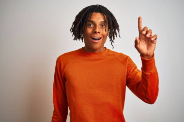 Kıvırcık beyaz arka plan üzerinde turuncu kazak giyen dreadlocks ile Afro Amerikan adam başarılı bir fikir parmak yukarı işaret. Çıkıldı ve mutlu. Bir numara.