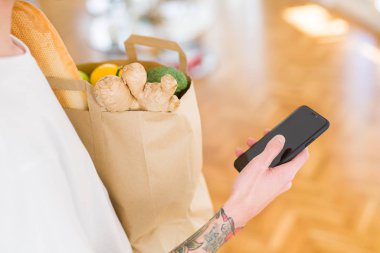 Genç yakışıklı adam tutan bir kağıt çanta dolu içinde taze bakkaliye bir