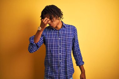 Sarı arka plan yorgun sürtünme burun ve gözleri yorgunluk ve baş ağrısı hissi üzerinde ayakta rahat gömlek giyen dreadlocks ile Afro adam. Stres ve hayal kırıklığı kavramı.