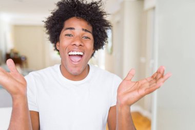 Afrika kökenli Amerikalı adam evde çılgın ve başarı için hayran kaldırdı Kollarını açarak kutluyor ve heyecanlı çığlık gözleri açık. Kazanan kavramı