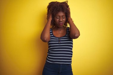 Genç Afrikalı Afro kadın izole sarı arka plan üzerinde çizgili t-shirt giyerek baş ağrısı umutsuz ve vurguladı çünkü ağrı ve migren. Eller baş.