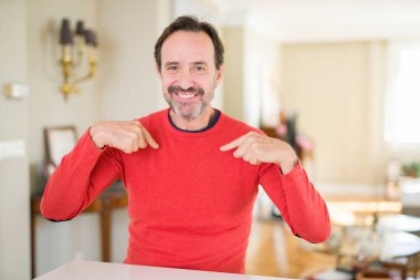 Yakışıklı orta yaş evde kendini gururlu ve mutlu parmakları ile işaret emin yüz, gülümseme ile seyir.