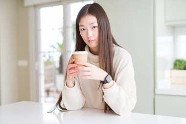 Bir kahve içme güzel Asyalı kadın akıllı yüz düşünme ciddi bir emin ifade ile kağıt fincan almak