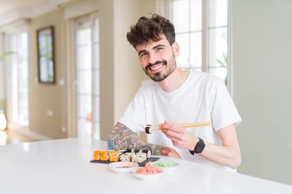 Young man eating sushi asian food using choopsticks