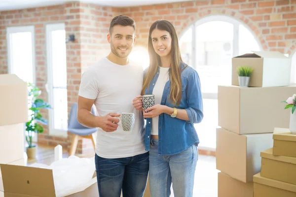Beautiful couple moving to a new house, smiling cheerful drinking a cup of coffee