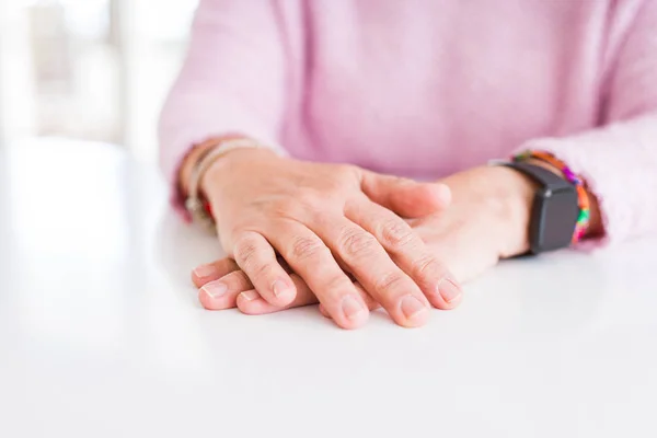 Крупним планом жінка середнього віку схрестила руки над білим столом — стокове фото