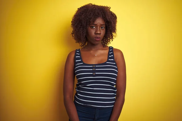 孤立した黄色の背景にストライプのTシャツを着ている若いアフリカのアフロ女性は懐疑的で神経質で 問題のために動揺して顔をしかめました 否定的な人 — ストック写真
