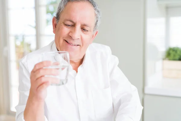 Knappe senior man houden een vers glas water en glimlachen — Stockfoto