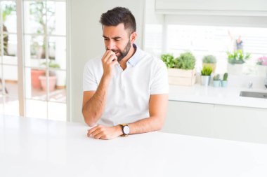 Evde yakışıklı İspanyol adam Casual beyaz t-shirt vurguladı ve ağız ısırma çivi elleri ile gergin bakıyor. Anksiyete sorunu.