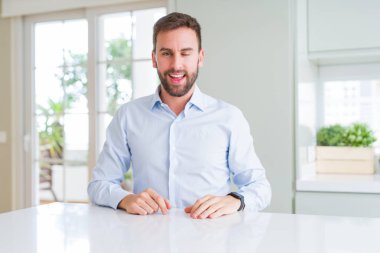 Seksi ifade, neşeli ve mutlu yüz ile kameraya bakarak yakışıklı iş adamı göz kırpıyor.