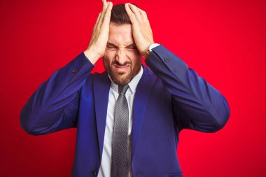 Genç yakışıklı iş adam üzerinde kırmızı izole arka plan baş ağrısı umutsuz ve vurguladı çünkü ağrı ve migren. Eller baş.