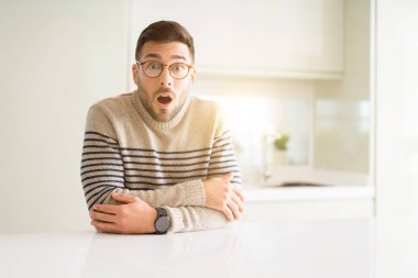 Evde gözlük takan genç yakışıklı adam sürpriz bir yüz ile şok korkmuş ve korku ifadesi ile heyecanlı korkuyor