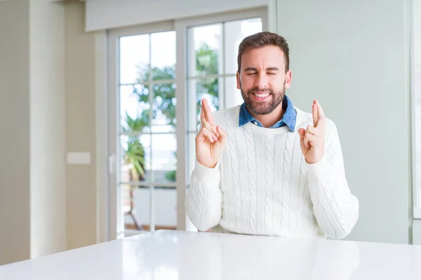 英俊的男人穿着休闲毛衣 微笑着交叉手指与希望和眼睛闭上 运气和迷信的概念 — 图库照片