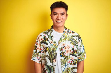 Asya Çinli adam tatil üzerine yaz gömlek giyiyor izole sarı arka plan üzerinde mutlu ve serin bir gülümseme yüz. Şanslı kişi.