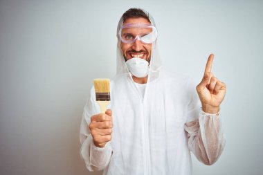 Profesyonel çalışan ekipman giyen ressam adam izole arka plan üzerinde fırça tutarak çok mutlu yan el ve parmak ile işaret