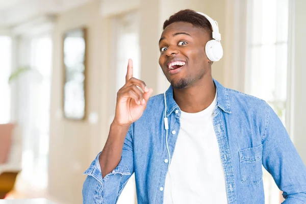 非洲裔美国男子戴着耳机听音乐 指着手指 提出成功的想法 退出和快乐 — 图库照片