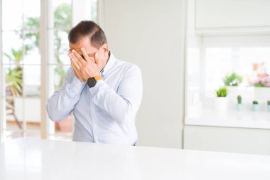 Orta yaş adam ağlarken elleri ile yüz kapsayan üzücü ifade ile evde oturuyor. Depresyon konsepti.