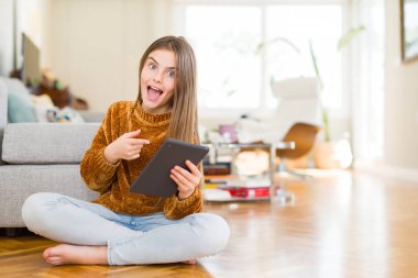 Güzel genç kız çocuk dijital Touchpad tablet kullanarak katta oturan çok mutlu el ve parmak ile işaret