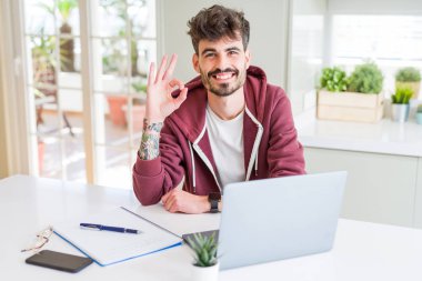 Bilgisayar laptop ve defter parmak, mükemmel sembolü ile ok işareti yapıyor kullanan genç öğrenci adam