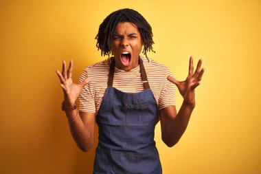 Kıvırcık sarı arka plan üzerinde apron giyen dreadlocks ile Afro Amerikan barista adam deli ve silah ile başarı için deli kutluyor kaldırdı ve heyecanlı çığlık kapalı gözleri. Kazanan kavramı