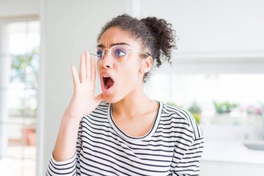 Bağırarak ve ağzı üzerinde el ile yan için çığlık gözlüklü afro saçlı güzel genç Afro-Amerikan kadın. İletişim kavramı.