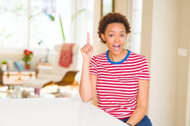 Genç güzel Afrikalı-Amerikalı kadın evde parmak ile başarılı fikir işaret. Çıktıktan ve mutlu. Bir numara.