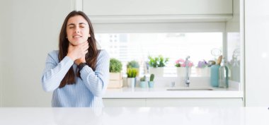 Güzel genç kadının evde beyaz masada oturan geniş açı resim bağırıyor ve çünkü ağrılı boğma boğulmak. Sağlık problemi. Asphyxiate ve intihar konsepti.