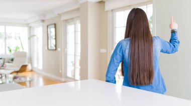 Uzun saçlı kot ceket giyen genç güzel Asyalı kadın ters parmak el ile öne işaret poz