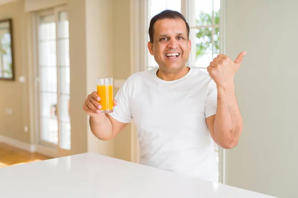 Hombre Mediana Edad Bebiendo Vaso Jugo Naranja Casa Señalando Mostrando — Foto de Stock