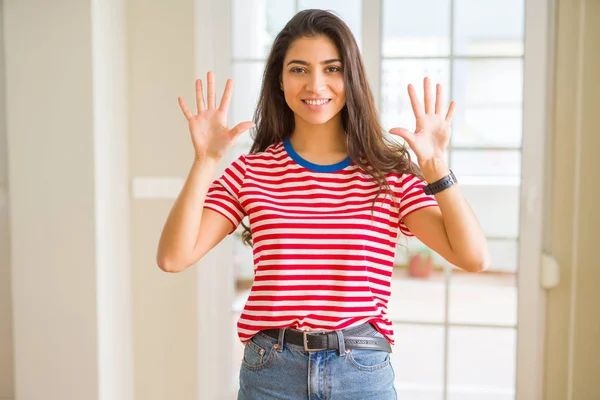 若くてきれいな女性の指で上向きの表示とカジュアルな シャツを着て数 自信を持って 幸せな笑みを浮かべて — ストック写真