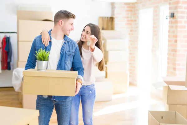 Schönes junges Paar, das sich verliebt umarmt und Schlüssel für neue h zeigt — Stockfoto