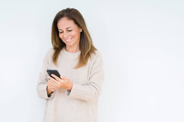 Orta yaş kadın ayakta mutlu bir yüz ile izole arka plan üzerinde akıllı telefon kullanarak ve dişleri gösteren kendinden emin bir gülümseme ile gülümseyerek