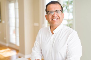 Evde kameraya gülümseyen gözlük takan orta yaş erkek