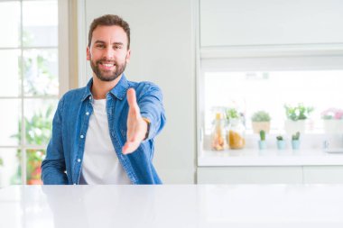Evde yakışıklı adam tebrik ve davetkar olarak dostu sunan el sıkışması gülümsüyor. Başarılı iş.