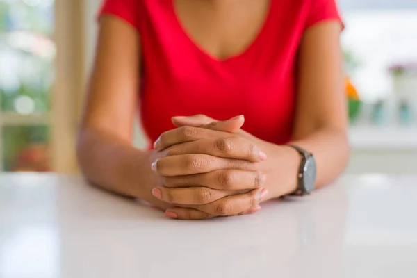 Close up de jovem mulher cruzando as mãos sobre a mesa branca — Fotografia de Stock