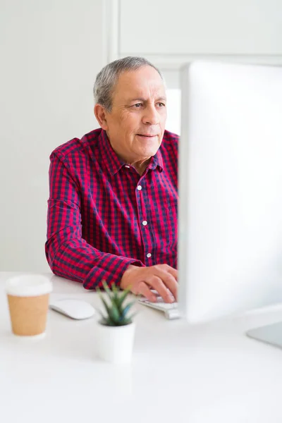 Hombre mayor guapo que trabaja usando la computadora y sonriendo confiado — Foto de Stock