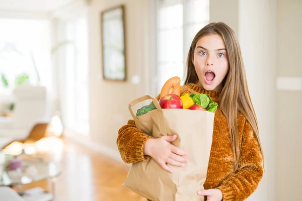 驚きの顔でショックに怯えた新鮮な食料品の紙袋を持つ美しい若い女の子は 恐怖表現で恐怖と興奮 — ストック写真