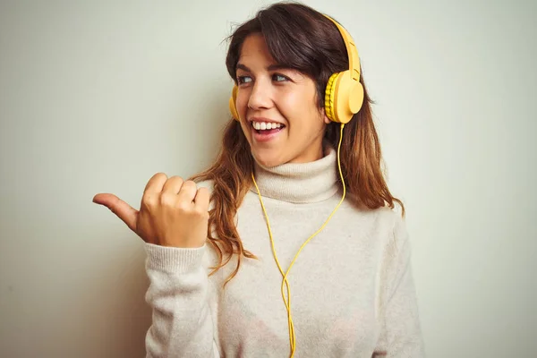 아름다운 여성은 배경을 헤드폰을 사용하여 음악을 행복한 얼굴을 손가락으로 측면을 — 스톡 사진